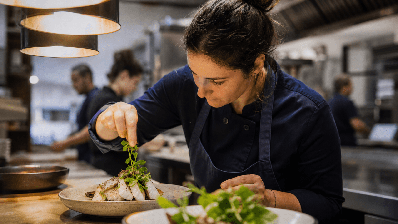 Une cheffe apporte la touche finale à une assiette